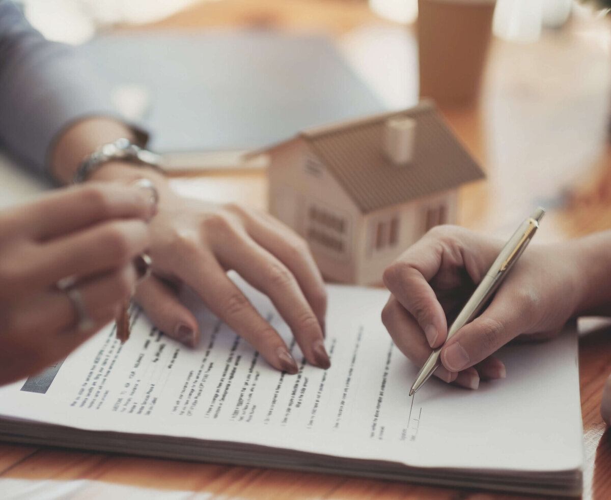 A licensed real estate agent and client sign documents for the purchase of a home